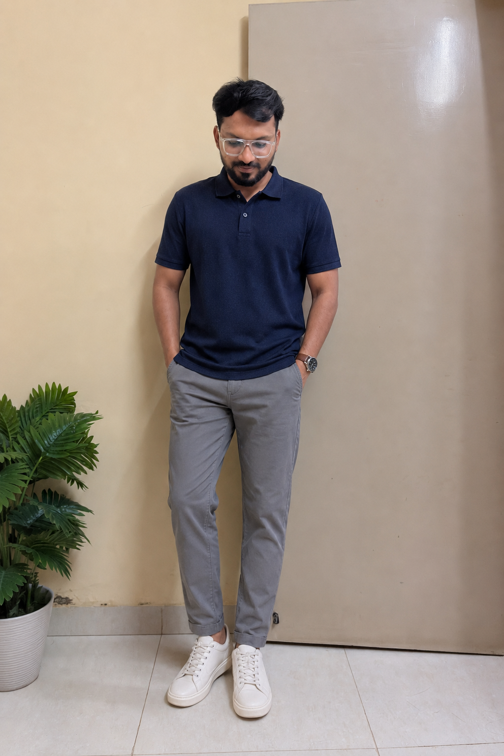 Indian man wearing a navy textured polo, stone chinos and off-white sneakers during the rainy season