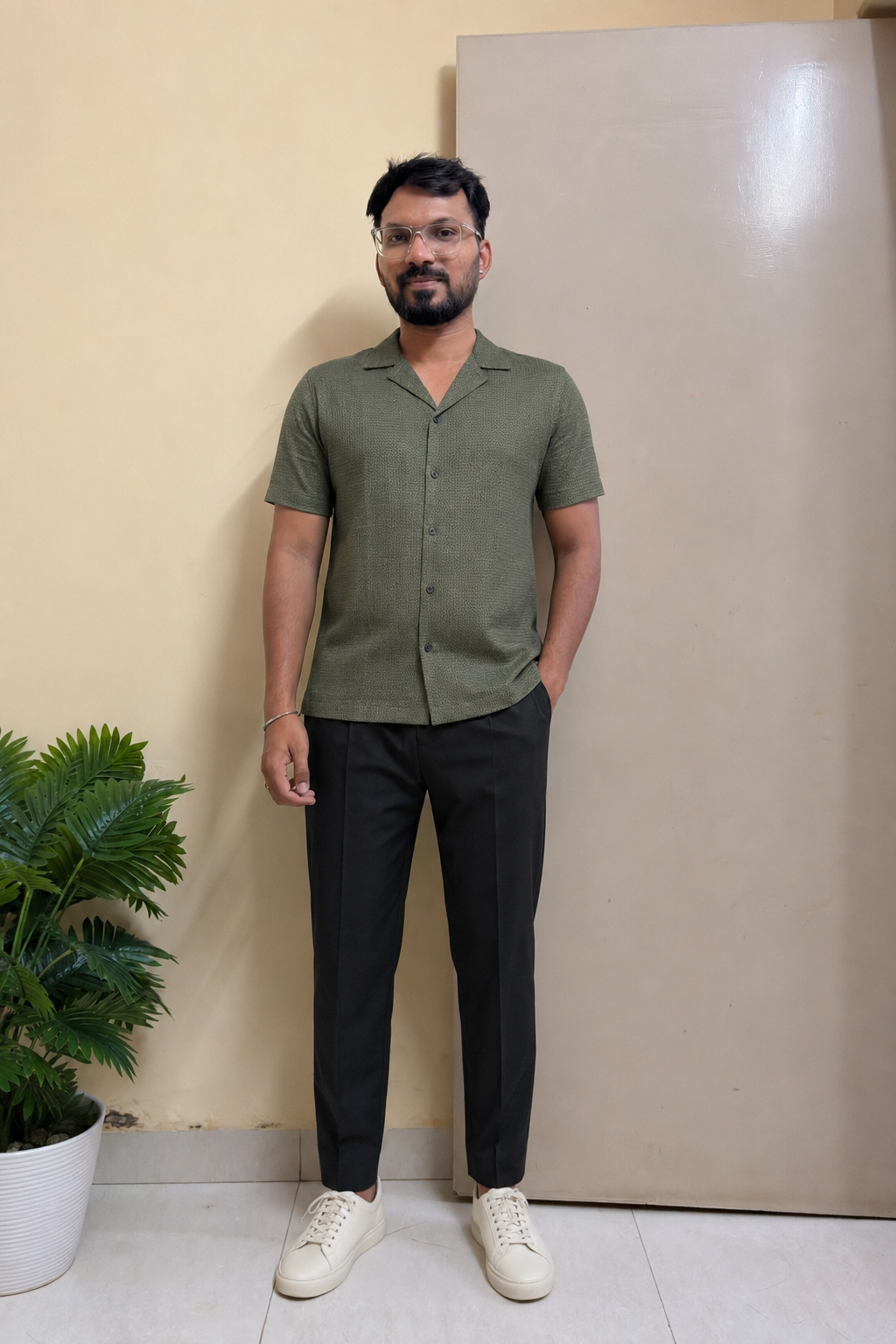 Indian man wearing a muted textured camp-collar shirt with black trousers and off-white sneakers