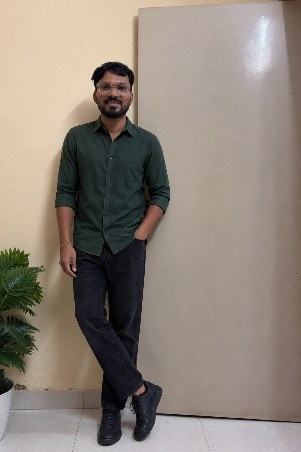 Indian man wearing a forest-green shirt, lightweight black jeans and dark sneakers during monsoon