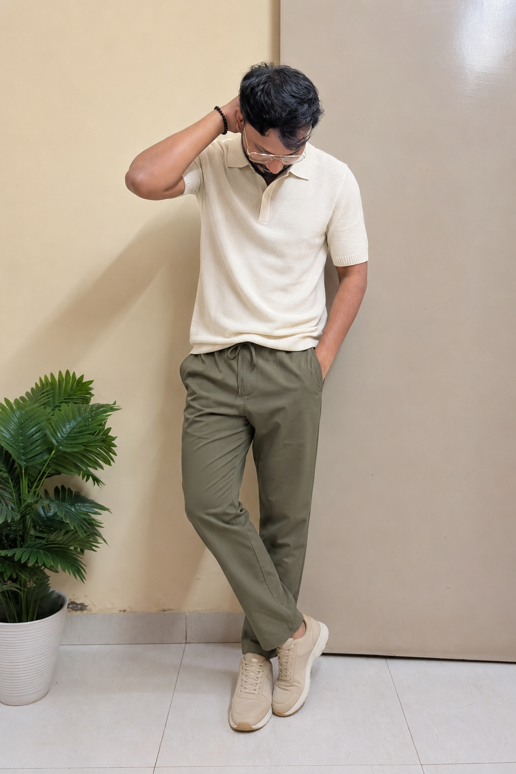 Indian man wearing a cream polo, olive technical trousers and beige sneakers for monsoon travel