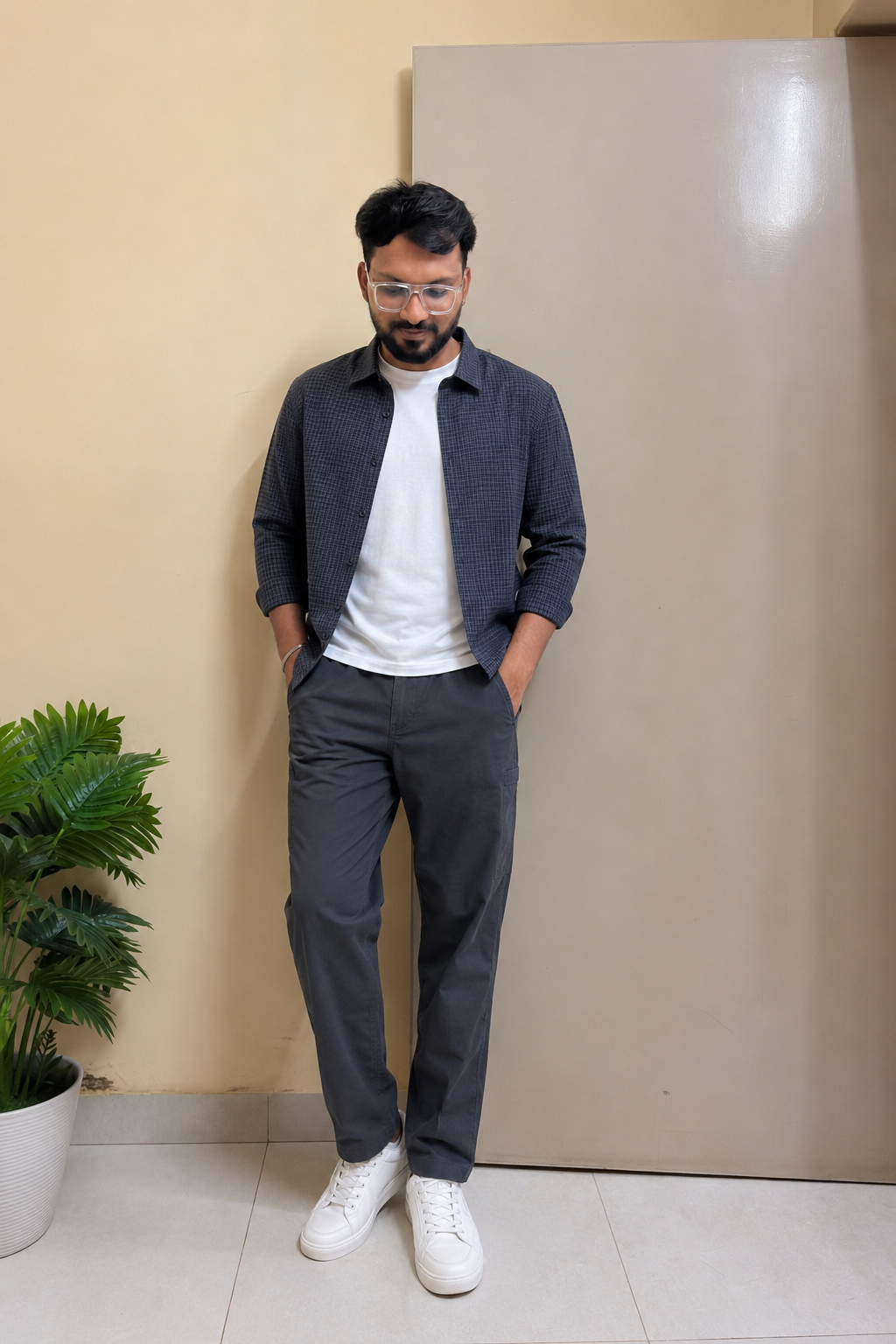 Indian man wearing a subtle checked overshirt, white T-shirt and charcoal trousers for college in monsoon