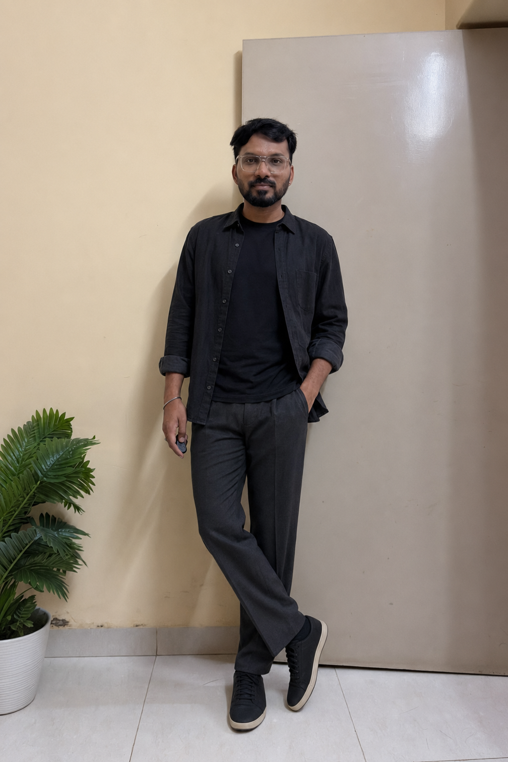 Indian man wearing a washed-black overshirt, black T-shirt and charcoal trousers in a monochrome monsoon outfit